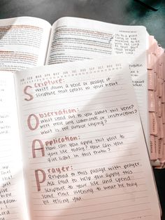 an open book sitting on top of a table next to a pile of paper notes