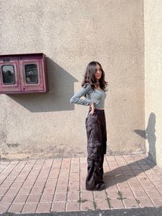 a woman standing in front of a wall with her hands on her hips