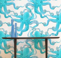 an octopus wallpaper with blue vases and candles on a table in front of it