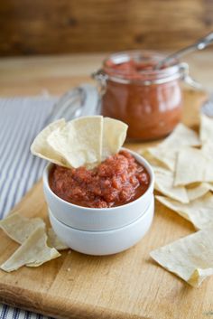 a wooden cutting board topped with chips and salsa