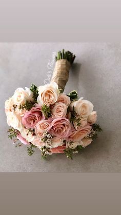 a bridal bouquet with pink and white flowers on the floor in front of a gray background