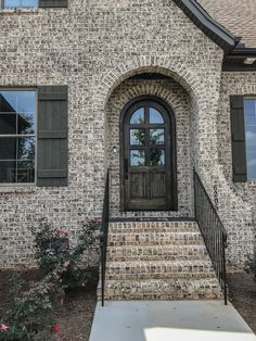 a brick house with black shutters and a front door that leads to the entrance