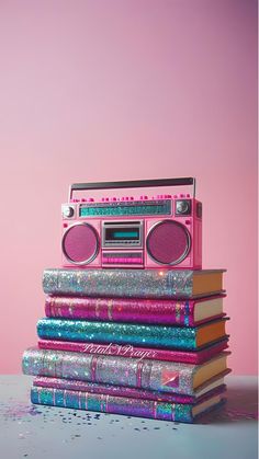 a stack of books with a pink boombox on top of each other and glitter covering the covers