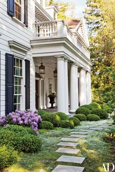 a white house with blue shutters and landscaping