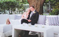 a man and woman sitting on a couch next to each other in front of a tree