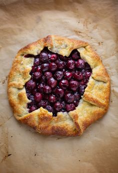 a pie with cranberries in the middle on top of parchment paper, ready to be eaten