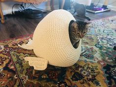 a cat is hiding in a crocheted ball on the floor next to a rug