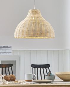 a wooden table topped with two chairs and a light hanging from it's ceiling