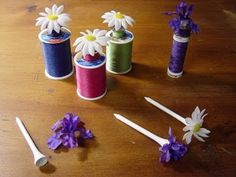 several spools of thread, flowers and scissors on a table with purple daisies