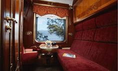 a red couch sitting next to a window on top of a wooden floored train