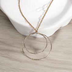 Elevate your style with this bold, mixed metal necklace designed for powerful, fashion-forward women. This unique piece features an original Lepa Jewelry design with two extra-large, open-frame Argentium Sterling Silver circles, one nested inside the other and artfully shaped into waves. These striking circles hang from a figure-8 gold-filled chain, giving the necklace an elegant mixed metal finish. The chain measures 18", and the pendant adds up to an overall length of approximately 21", making it a statement piece perfect for career-oriented women who wear jewelry to feel empowered and chic. Crafted from high-quality, heavy-gauge metals, this necklace stands out from average circle necklaces with its thoughtful design and superior craftsmanship. Whether it's a gift for a special occasion Everyday Silver Brass Chain Necklace, Brass Box Chain Necklace, Modern Silver Brass Necklace, Everyday Metal Necklace With Polished Finish, Modern Hammered Round Necklace, Hand Forged Round Metal Necklace, Modern Hammered Metal Necklace, Minimalist Polished Brass Necklaces, White Gold Brass Necklace With Round Pendant