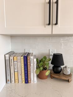 a shelf with books and a lamp on it in the corner of a kitchen counter