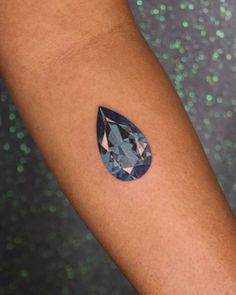 a woman's arm with a blue and pink diamond tattoo on her left arm