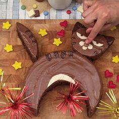 a person decorating a cake with chocolate frosting and sprinkles on a wooden table