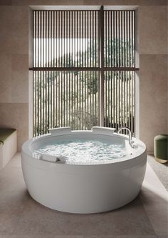 a large white bath tub sitting next to a window with blinds on it's side