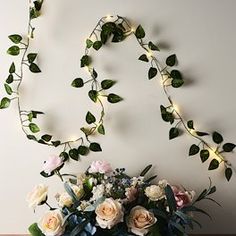 a vase filled with flowers sitting on top of a table next to a string of lights