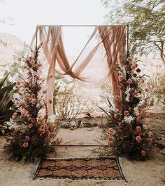 an outdoor wedding ceremony setup with flowers and greenery on the ground, surrounded by desert plants