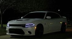 a white dodge charger parked on the street at night