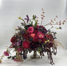 a vase filled with lots of different types of flowers on top of a white table