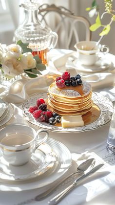 pancakes with berries and blueberries are served on a table set for breakfast or brunch