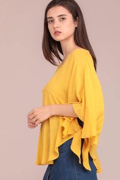 Ruffle poncho sleeves Poncho top with side tie and V-neck Materials: 100% Cotton Color: Yellow Model is 5'8" and wearing a Small Oversized V-neck Poncho For Spring, Spring Chic Poncho With Batwing Sleeves, Chic Spring Poncho With Batwing Sleeves, Spring Bell Sleeve Tops With Tie Sleeves, V-neck Tops With Tie Sleeves For Brunch, V-neck Top With Tie Sleeves For Brunch, Poncho Style Top, Goldenrod Yellow, Poncho Top