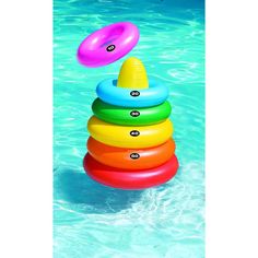 an inflatable pool toy floating on top of a stack of colorful rings next to a swimming pool