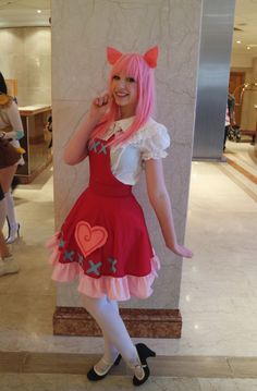 a woman with pink hair is posing for the camera in a red and white dress