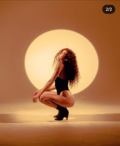 a woman kneeling down in front of a full moon with her hands on her knees