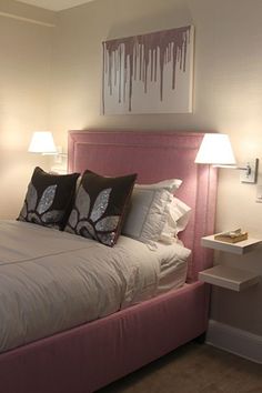 a bed with white sheets and pink headboard