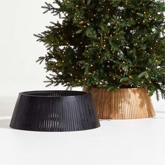 a potted christmas tree next to a black trash can with lights on the top