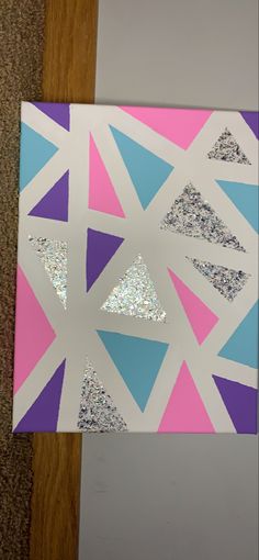 a piece of paper that has been cut into triangles with glitter on it and is laying on the floor