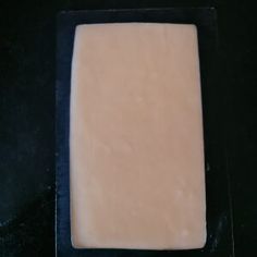 a square piece of food sitting on top of a black counter next to a knife