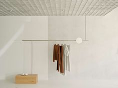 an empty room with clothes hanging on the wall and a wooden block in front of it