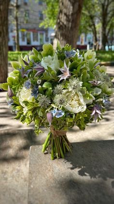 a bouquet of flowers sitting on top of a cement slab in the park next to trees