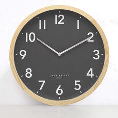 a black and gold clock with white numbers on the face is shown in front of a white wall