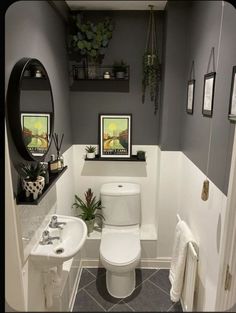 a white toilet sitting in a bathroom next to a sink under a mirror and potted plants