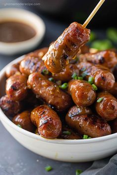 a white bowl filled with meat covered in sauce and toothpicks on a stick