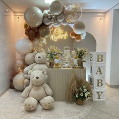 a teddy bear sitting in front of a baby shower with balloons on the wall behind it