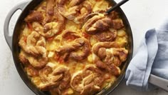 a casserole dish with meat and cheese in it next to a blue napkin