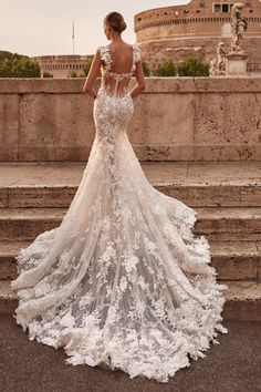 a woman in a wedding dress is standing on some steps with her back to the camera