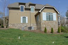 a brown house with white windows and green grass