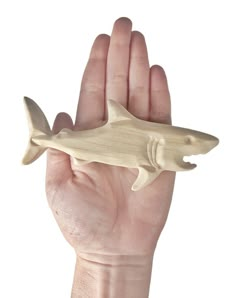 a hand holding a wooden toy shark in it's palm