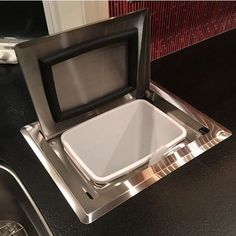 an open microwave sitting on top of a black counter