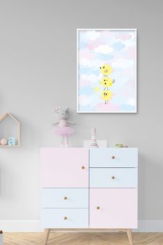 a baby's room with pink and blue dressers, toys and wall art