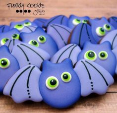 blue decorated cookies with green eyes and black cat's eyes on them, sitting on a wooden surface