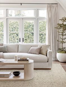 a living room with white couches and large windows in the ceiling, along with a rug on the floor