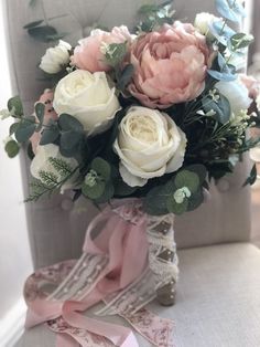 a bouquet of flowers sitting on top of a chair next to a pink ribbon tied around it