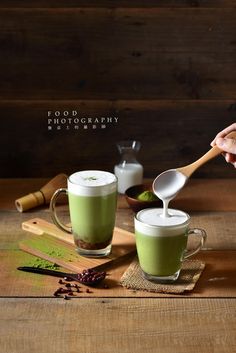 two mugs filled with green liquid on top of a wooden table