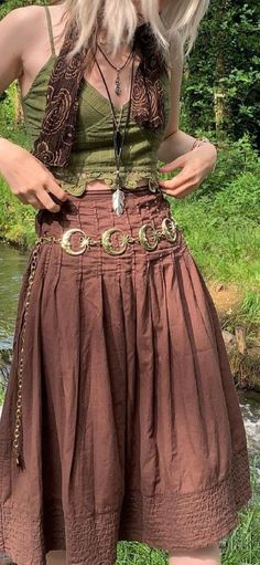 a woman with blonde hair wearing a brown skirt and green tank top standing in front of a river