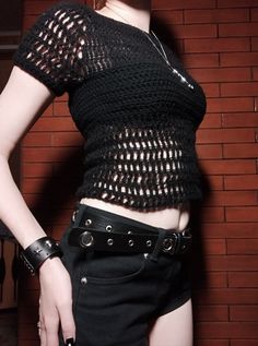 a woman in black shirt and shorts standing next to brick wall with her hand on her hip